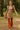 Woman walking in ribbed long sleeve mini sweater dress latte with fringe bag, forest daylight.