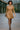 Model striding in ribbed long sleeve mini sweater dress latte with clutch, modern glass hall.