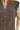 Close-up of coffee brown linen fabric with ruffle seam and pearl button