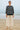 Woman wearing a black and white striped sweater and beige pants on a beach.