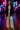 Woman in black fringe blazer, silver set, silver heels, holding clutch, neon street night scene