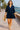 Woman walking riverside in summer navy mini dress and sandals, sunny day