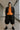 Facing camera in textured cotton-blend shirt with oversized blazer and platform shoes, glass hallway