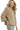 Side view of taupe textured knit V-neck top highlighting textured surface and stretch fit.