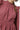 Close-up of textured fabric and ruffle shoulder detail in dusty rose