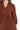 Close-up of corduroy texture and tiered seam details in red-brown fabric