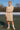 White model in beige turtleneck sweater dress with sneakers and headband on snowy tennis court