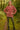 Woman standing in dark red turtleneck sweater, with hiking boots, forest path lighting