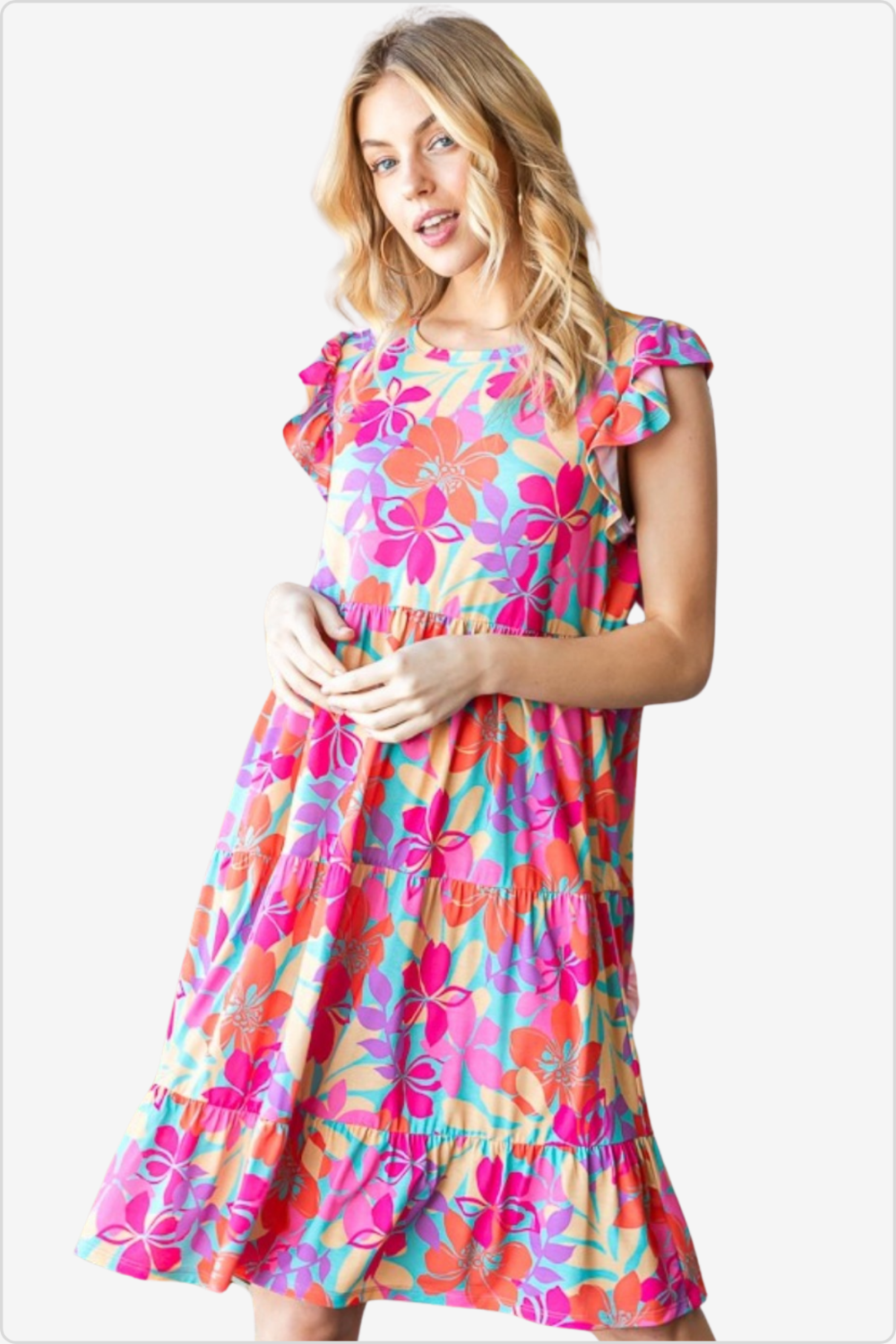 Woman beams in a brightly colored floral ruffle dress, perfect for a playful summer look.