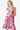 Woman beams in a brightly colored floral ruffle dress, perfect for a playful summer look.