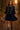 Woman walking forest path in navy mini dress and boots, autumn leaves