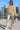 Woman posing in Wide Neck Band Drop Shoulder Sweater with silver pants and sneakers, rooftop daylight.