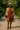 Rust knit set with trench coat and heeled booties, styled with straw hat and black crossbody