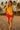 Walking on sand in yellow floral blouse with wrap sandals, tropical beach at sunset