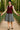 Woman posing in maroon zip front vest with lace blouse and denim skirt, forest bridge afternoon light.