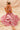 Woman in a pink floral dress sitting on a beige fabric background