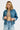 Woman wearing a denim jacket and light blue jeans on a white background