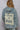 Back view of dusty blue jacket with relaxed cut and visible panel seams