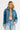 Woman wearing a denim jacket and jeans on a plain background