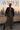 Woman in checker dress with leather jacket and boots on rooftop at sunset