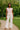 Woman wearing blush striped sweater and ivory wide-leg pants in a park