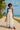 White maxi dress with blue denim trim and sea-themed print, tied straps and relaxed fit for summer style.