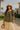Woman in floral babydoll top with straw hat and cream skirt near beach villas