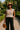 Woman in mocha knit sweater, black pants, and tan hat walking in a sunny park
