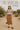 Woman in mocha striped knit sweater and brown skirt standing in a desert landscape