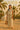 Woman in beige linen jumpsuit barefoot in desert with palm trees and tent