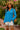 Woman in babydoll blouse, white shorts, and straw bag in garden setting