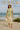 Woman wearing sage ribbed top and light beige skirt with straw hat by the ocean