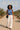 Woman in striped crop tank and white trousers walking in a desert landscape