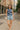 Woman in striped knit crop tank and light blue shorts walking confidently in the city