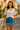 White crochet short sleeve top styled with denim skirt and straw bag.