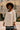 Woman in white swing top, jeans, and wide-brim hat standing confidently