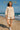 Woman in white swing top and shorts walking on a sunny beach