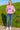 Woman in Acid Washed Oversized T-Shirt with jeans and white sneakers, walking on hill with flowers, daylight