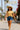 Model wearing striped knit top with denim shorts, straw hat, and white crossbody bag