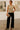 Woman in beige sleeveless top and black pants standing in an art gallery.