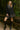 Smiling woman in polka dot plaid trim babydoll dress, black knee-high boots, beret, wooden bridge in forest