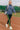 Model walking on stadium track in blue indigo scuba sweatshirt with striped leggings and sneakers, sporty.
