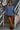 Smiling woman leaning on stair rail in blue indigo scuba sweatshirt with leather shorts and loafers, graffiti.