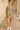 Woman in paisley boho mini dress with beige biker shorts and white sneakers in arched walkway