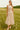 Woman standing in Bow Tie Crop Top and Tiered Skirt Set with pink flats, in daisy field, daylight