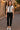  Woman standing in Button-Down Knit Sweater Shirt with black pants and loafers, on cobblestone street, evening lights