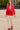 Woman in fuchsia-red color block blazer with white pants walking in city square