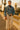 Holding camera in cropped denim jacket with wide-leg pants and flats, on ornate Paris bridge, sunset glow