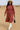 Model walking in sandy desert in dusty rose textured midi dress with white boots and wide-brim hat, daylight