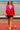 Stylish woman in fuchsia-red blazer and black shorts walking on stadium track